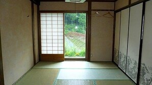 A traditional Japanese room with tatami flooring, sliding doors, and a view of a garden. - Minshuku Yurika (Urugi)