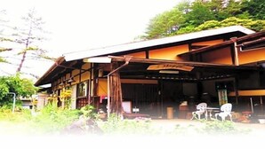 A traditional Japanese building with a covered porch, wooden beams, and a signboard. - Minshuku Yurika (Urugi)