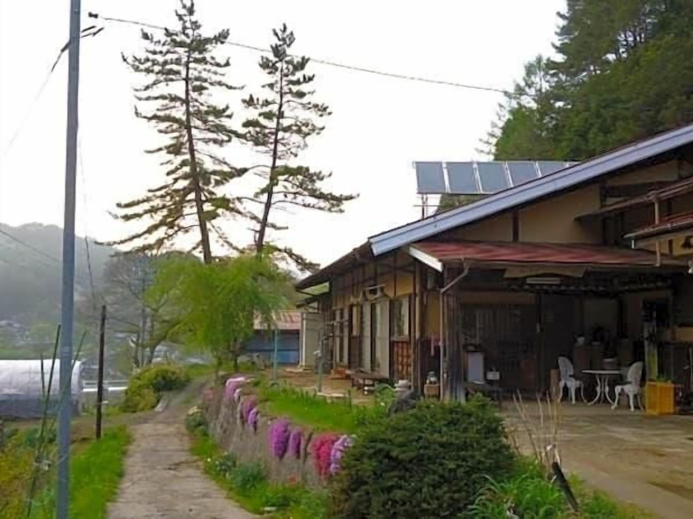 A traditional Japanese house with a covered porch, a pathway, and a small garden area.