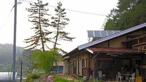 A traditional Japanese house with a covered porch, a pathway, and a small garden area.