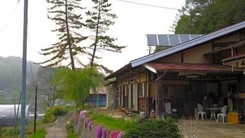A traditional Japanese house with a covered porch, a pathway, and a small garden area.