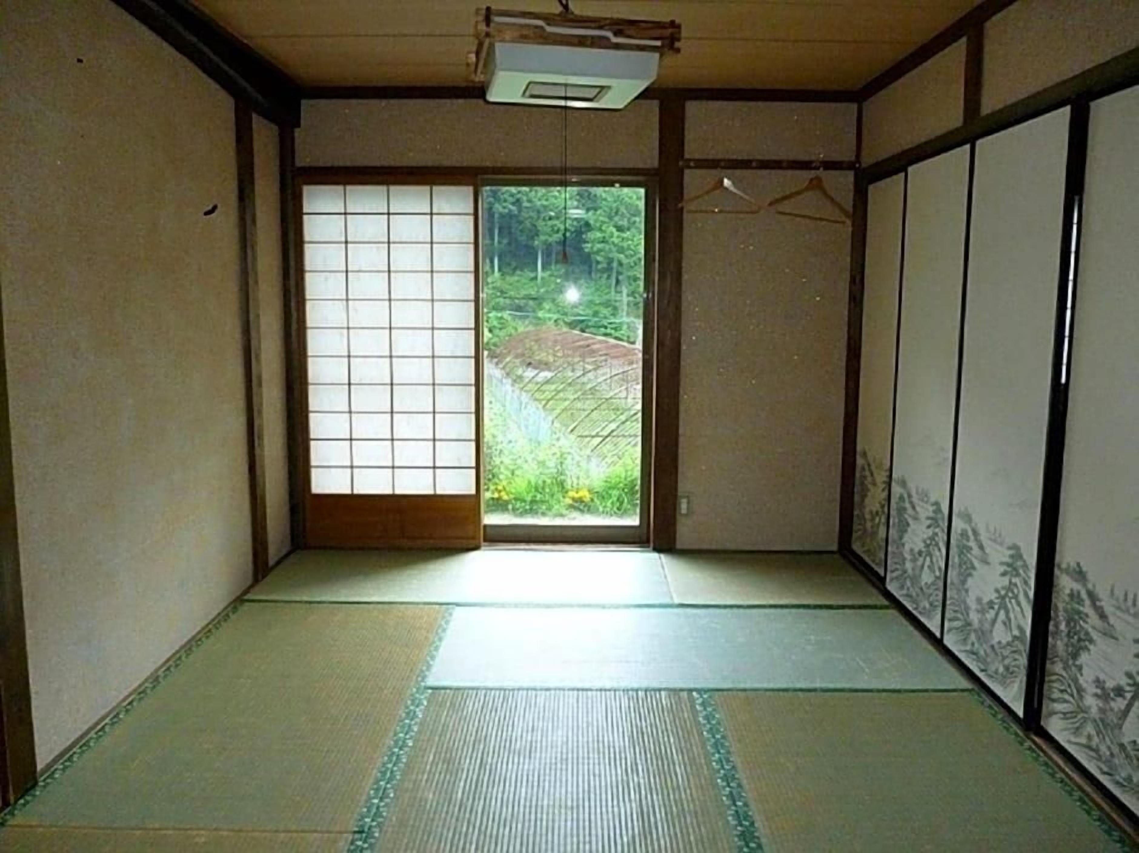 A traditional Japanese room with tatami flooring, sliding doors, and a view of a garden.