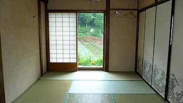 A traditional Japanese room with tatami flooring, sliding doors, and a view of a garden.