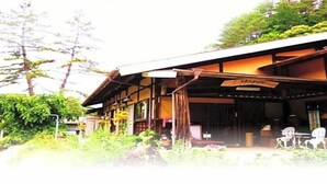 A traditional Japanese building with a covered porch, wooden beams, and a signboard.