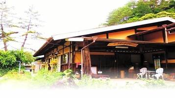 A traditional Japanese building with a covered porch, wooden beams, and a signboard.