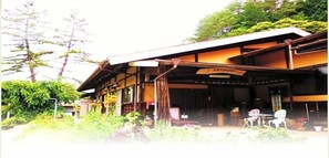A traditional Japanese building with a covered porch, wooden beams, and a signboard. - Minshuku Yurika (Urugi)