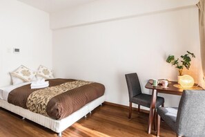 Une chambre d’hôtel avec un lit, une table et deux chaises, ainsi qu’une plante en pot.