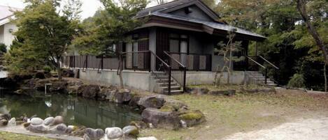 A traditional Japanese-style building with a stone pathway leading to a pond.