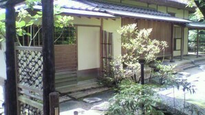 Un edificio tradicional japonés con techo de paja, puertas de madera y un camino de piedra que lleva a la entrada.