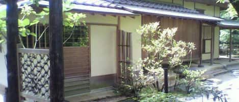A traditional Japanese-style building with a thatched roof, wooden doors, and a stone pathway leading to the entrance.