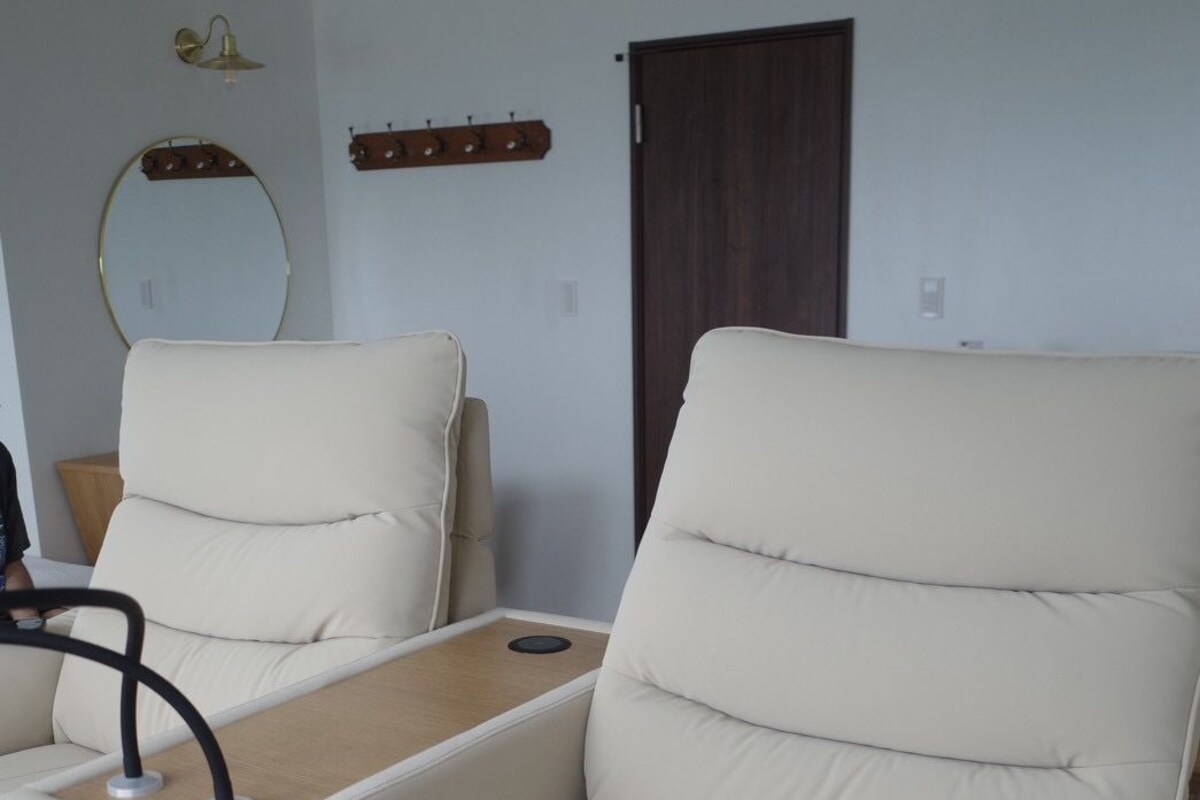 A modern living room with a beige sofa, a wooden side table, and a wall-mounted light fixture.