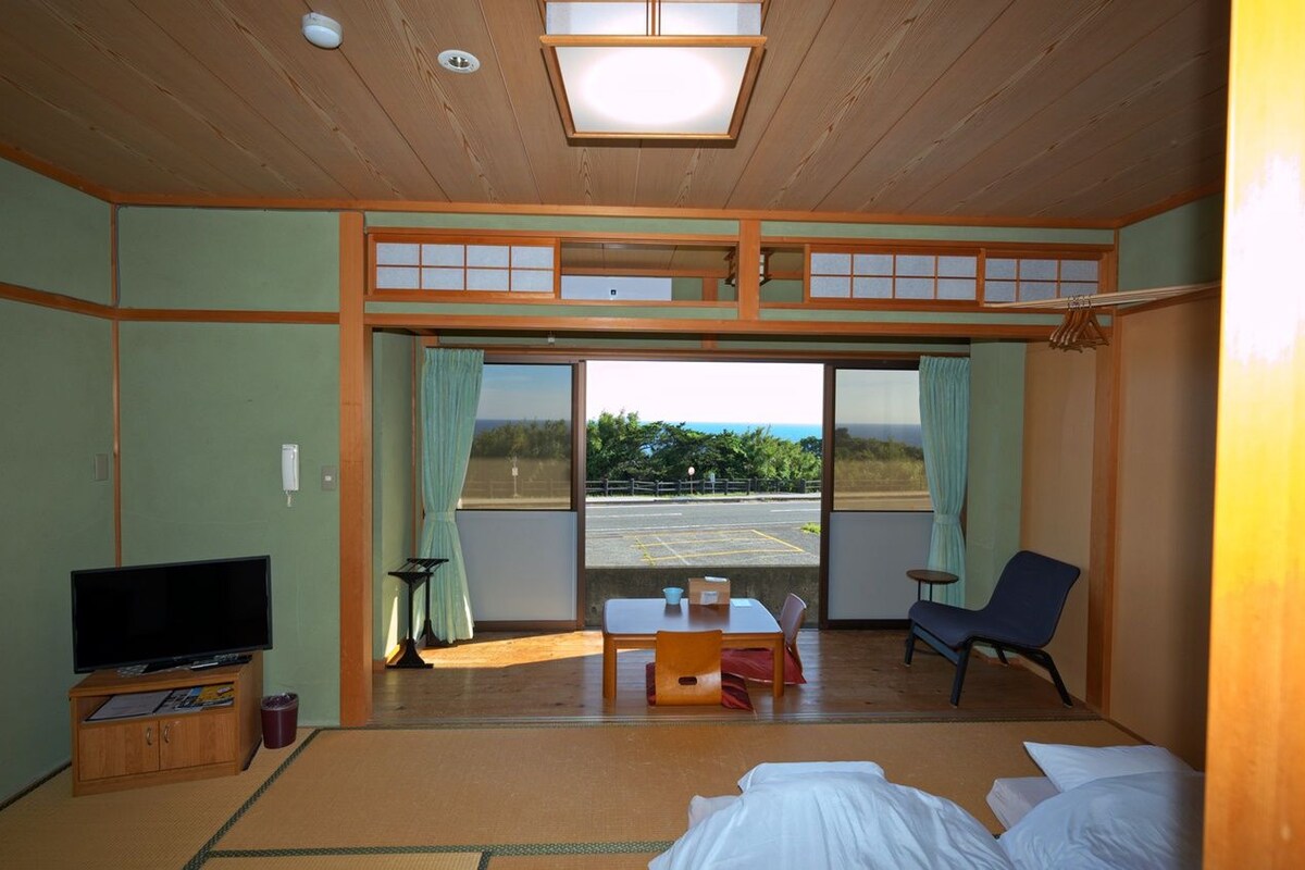 A room with a bed, a TV, a table, and a chair.