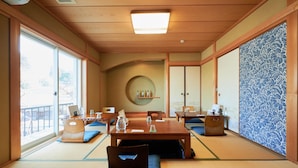 A traditional Japanese room with tatami flooring, a low table with cushions, and sliding doors. - Musubi no Koyado En (Kobe)