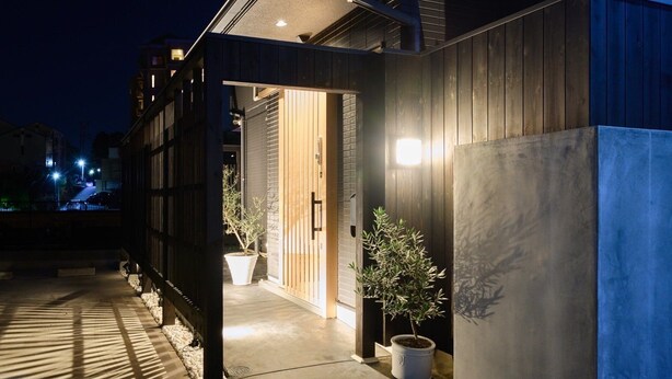 A modern building with a wooden exterior, a concrete pathway, and potted plants. - Musubi no Koyado En (Kobe)