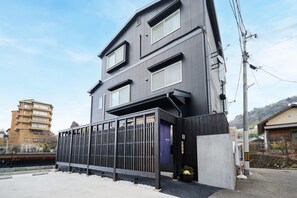 A modern two-story building with a dark facade, large windows, and a gated entrance. - Musubi no Koyado En (Kobe)