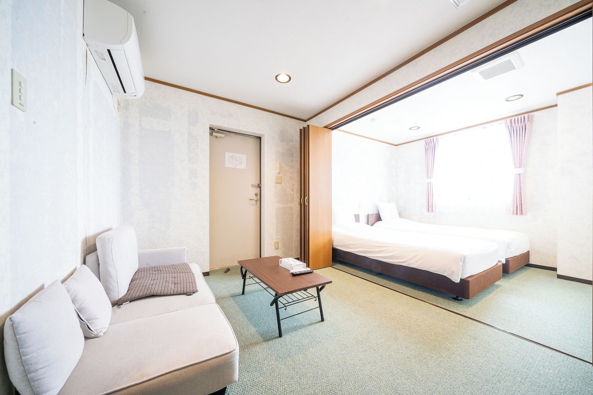 Une chambre d’hôtel équipée d’un lit, d’un canapé, d’une petite table et d’un appareil de climatisation.