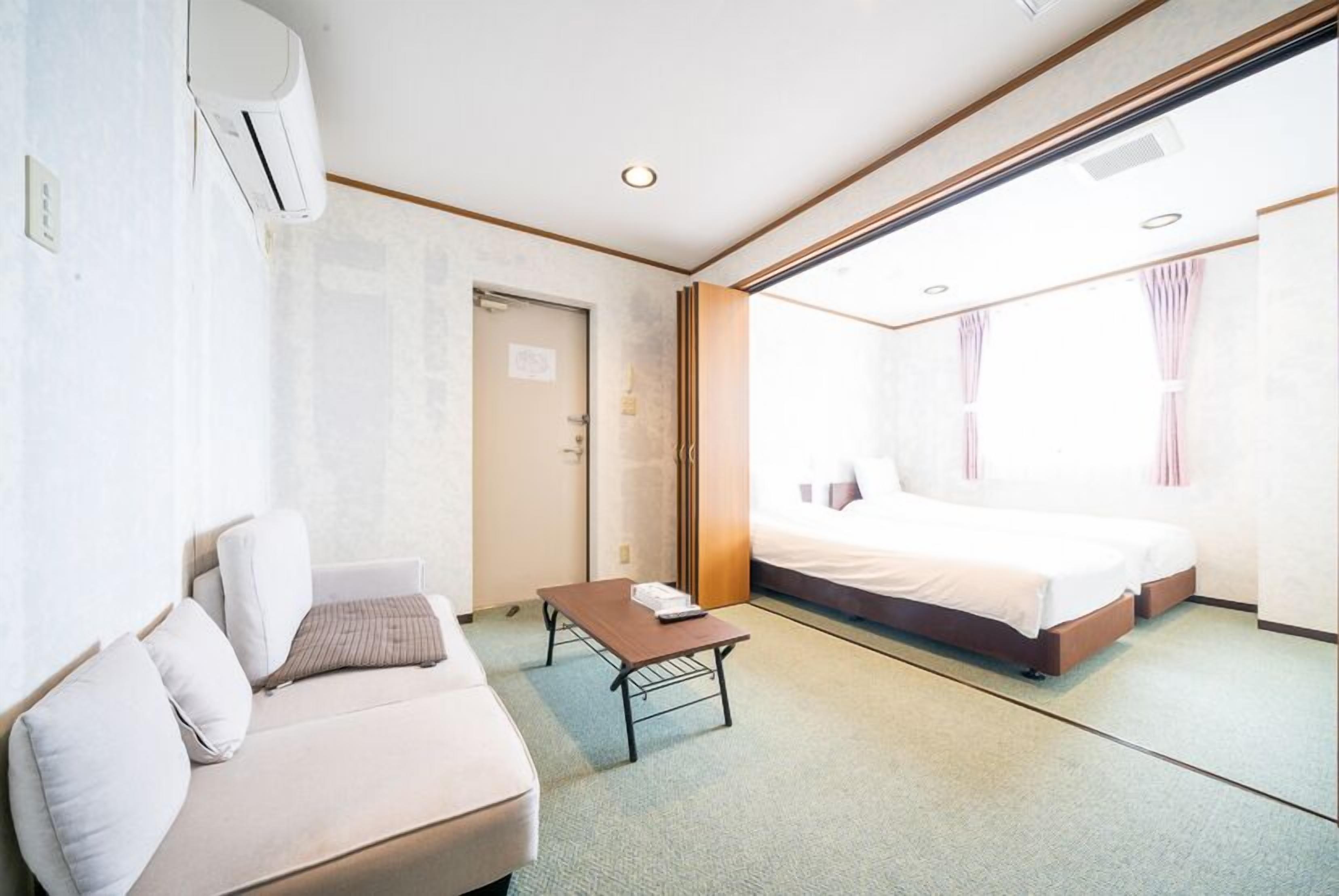Une chambre d’hôtel avec un lit, un canapé, une petite table et une porte.