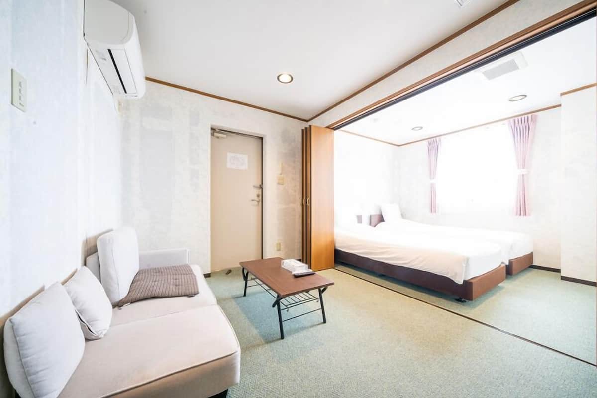 Une chambre d’hôtel avec un lit, un canapé, une petite table et une porte.