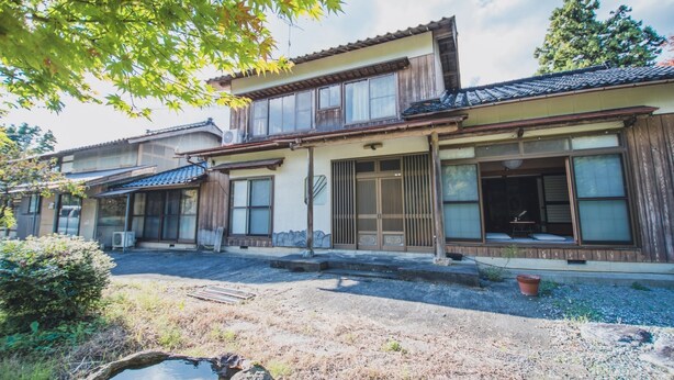 A traditional Japanese house with a wooden exterior, large sliding doors, and a small garden area with a pond. - Active Art Hotel (Sado)