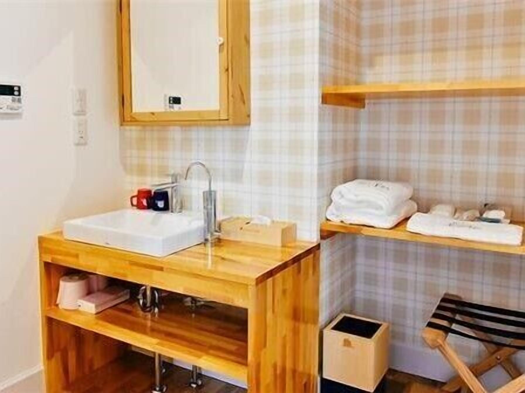 Une salle de bain avec un meuble-lavabo en bois, un évier, un miroir et une étagère avec des serviettes.