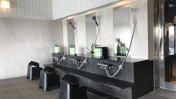 A modern bathroom with a black granite vanity, three sinks, and a large mirror.