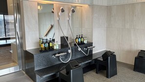 A modern bathroom with a granite countertop, a large mirror, and a shower with two handheld showerheads. - Plaza Annex (Fujisawa)