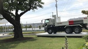 A white Isuzu truck parked on a grassy area with a tree and a fence in the background. - Plaza Annex (Fujisawa)
