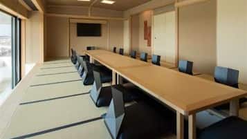 A conference room with a long table, chairs, and a television screen on the wall.