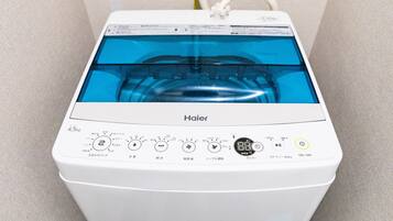 A white Haier washing machine with a transparent water tank, control panel with multiple settings, and a power cord plugged in.