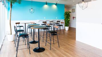 A modern interior with wooden flooring, a blue accent wall, and multiple seating arrangements including tables and chairs.