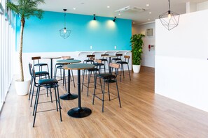 A modern interior with a blue accent wall, wooden flooring, and a mix of round and square tables with black chairs. - Mr. Kinjo in Motobu (Motobu)