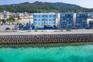 A modern building with multiple floors, a parking lot, and a waterfront view. - Mr. Kinjo in Motobu (Motobu)
