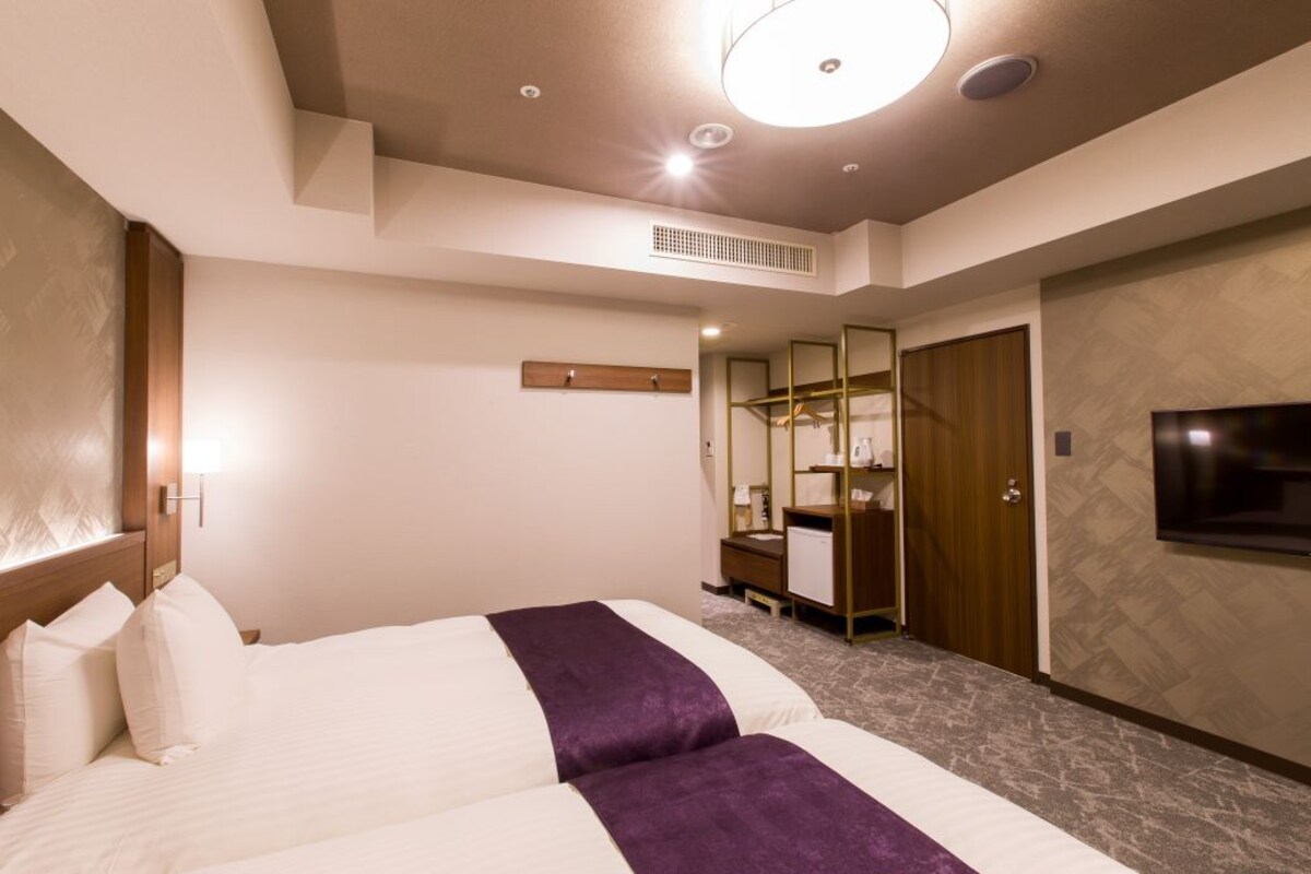 Una habitación de hotel con una cama grande, televisión, armario y espejo.