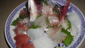 Un plato de sashimi con distintos pescados y guarniciones.