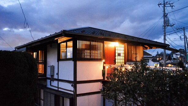 Een traditioneel Japans huis met pannendak, houten balken en een klein terras.