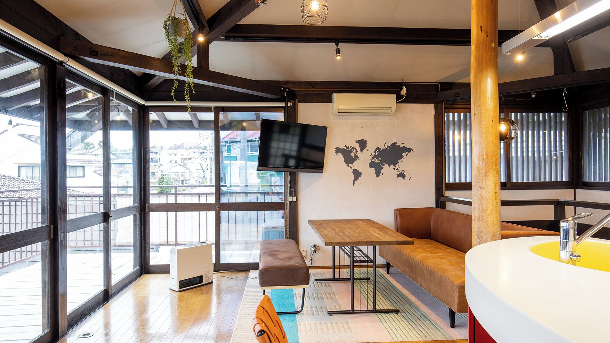 Un intérieur moderne avec un banc en bois, une table, un téléviseur et une carte du monde accrochée au mur.