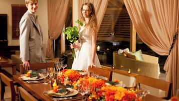 A dining area with a long table set for a meal, featuring a floral centerpiece and candles.
