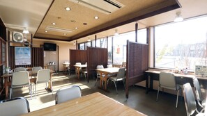 Un interior de restaurante con mesas, sillas, un menú y vistas a través del ventanal.