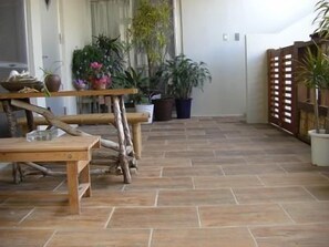 A room with a wooden floor, a table with chairs, and several potted plants.