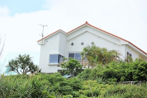 A two-story building with a red-tiled roof, a satellite dish, and a balcony.