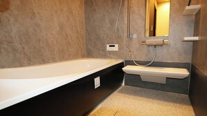 A modern bathroom with a freestanding bathtub, a built-in sink, and a mirror above the sink. - Yadoya Matsumoto Honjo (Matsumoto)