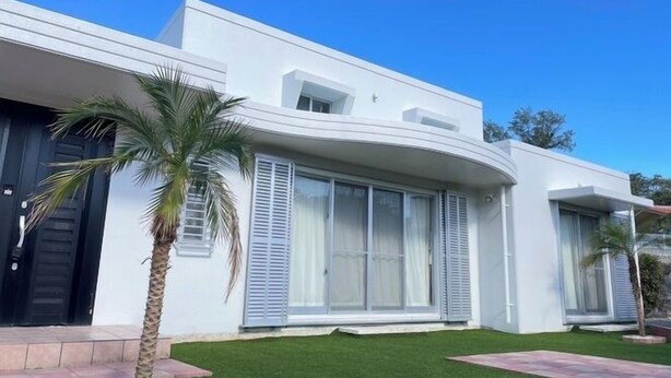 A modern two-story house with large windows, a flat roof, and a well-maintained lawn. - Rose Terrace Bise (Motobu)