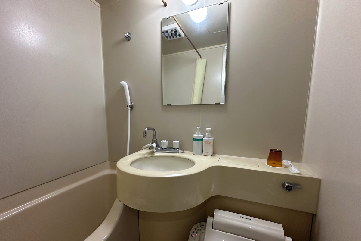 A bathroom with a sink, mirror, toilet, and shower.