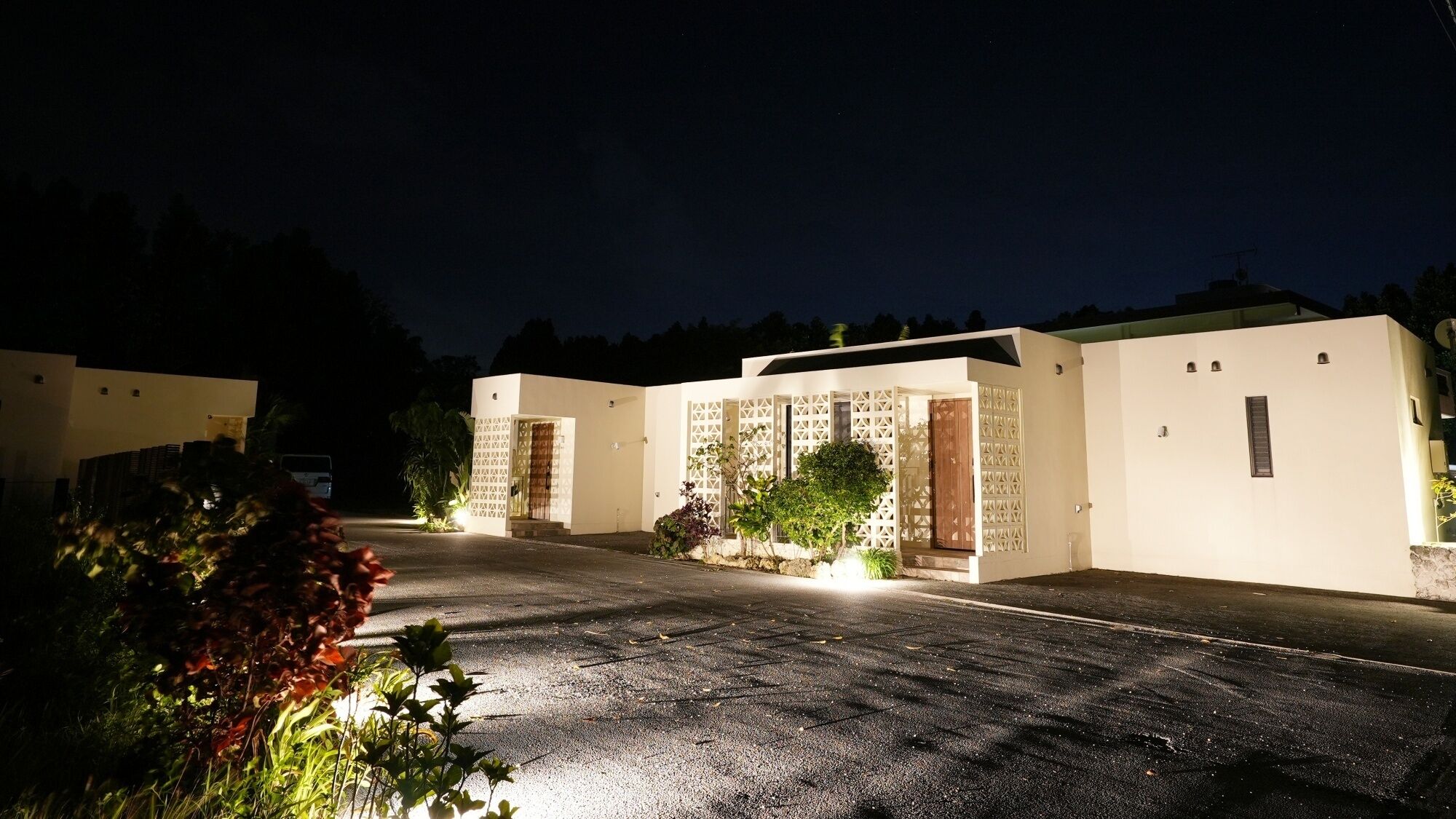 A modern building with a gated entrance, a driveway, and surrounding vegetation.