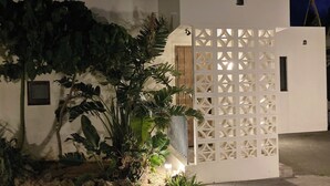 A white building with a wooden door and a decorative white lattice panel. - Bise Nob's Village (Motobu)