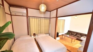A room with two beds, a sofa, a table, and a ceiling light fixture. - T-reef Vacation House Pine Tree (Kamakura)