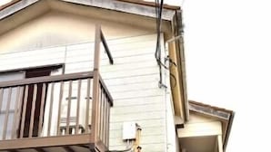 Un bâtiment à deux étages doté d’un balcon en bois, d’un escalier menant à l’étage supérieur et d’une enseigne indiquant un commerce ou un service.
