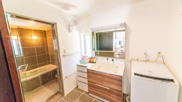 A bathroom with a shower, a sink, a mirror, and a toilet.