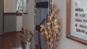 Un corridoio con un arco decorativo, un'opera d'arte incorniciata e un vaso con fiori secchi.