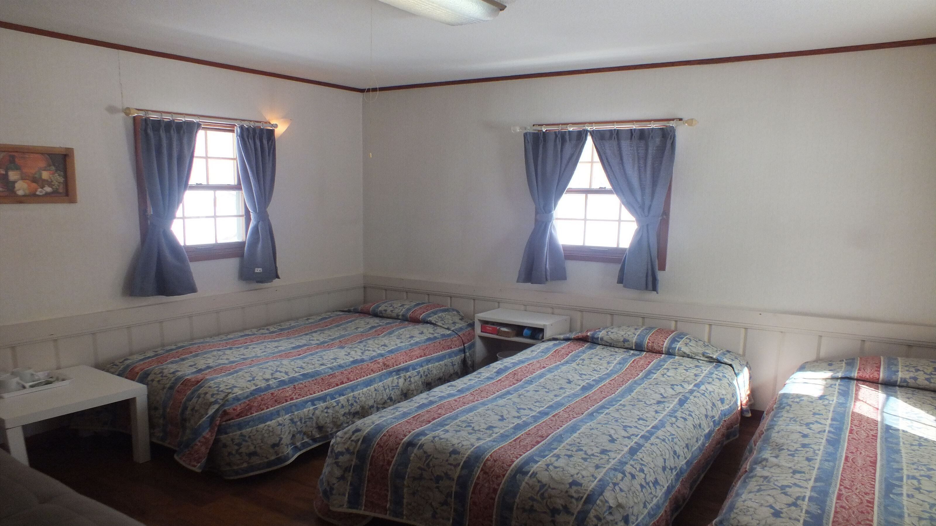 Una habitación con dos camas individuales, una mesita y una mesilla de noche.